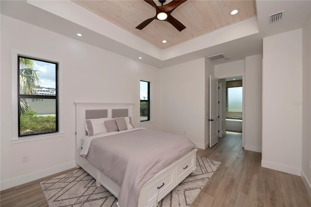 bedroom with a tray ceiling, ceiling fan, light hardwood / wood-style floors, and wood ceiling