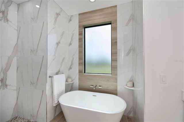 bathroom with a bathing tub and tile walls