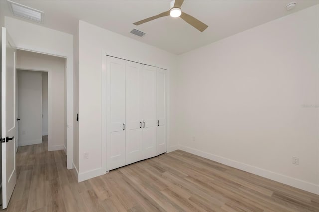 unfurnished bedroom with ceiling fan, light wood-type flooring, and a closet