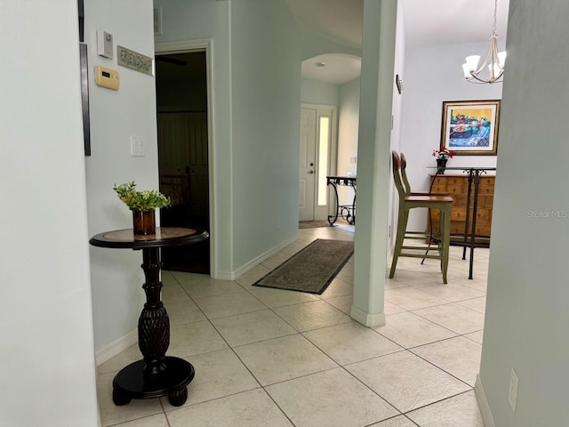 hallway with a chandelier and light tile flooring