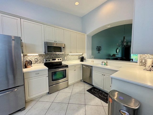 kitchen with appliances with stainless steel finishes, sink, tasteful backsplash, and light tile floors