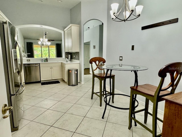 kitchen with stainless steel appliances, pendant lighting, a chandelier, tasteful backsplash, and light tile flooring