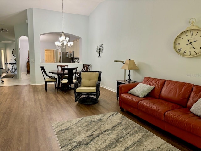 living room featuring high vaulted ceiling, dark hardwood / wood-style floors, and an inviting chandelier