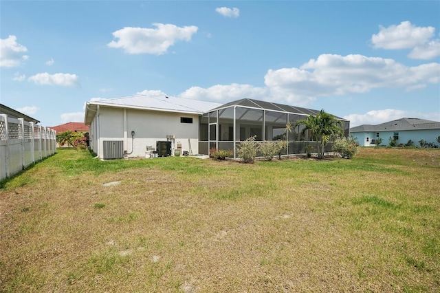 rear view of property with a lawn, glass enclosure, and cooling unit