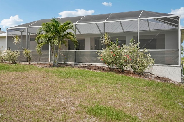 back of house with glass enclosure and a yard