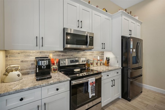 kitchen with white cabinets, light wood-type flooring, backsplash, and stainless steel appliances