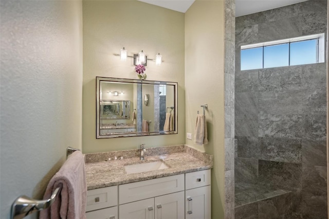 bathroom featuring tiled shower and vanity