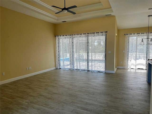 empty room featuring a raised ceiling, crown molding, and hardwood / wood-style floors