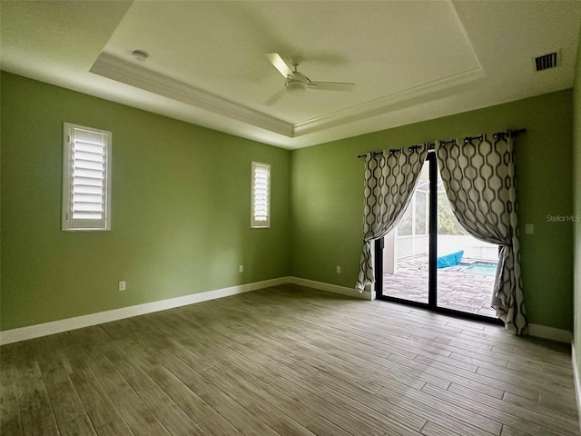 spare room featuring a tray ceiling, ceiling fan, and wood-type flooring