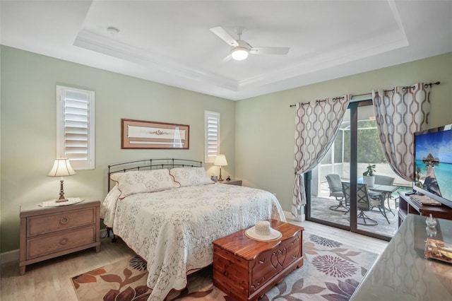 bedroom with a tray ceiling, access to outside, and multiple windows