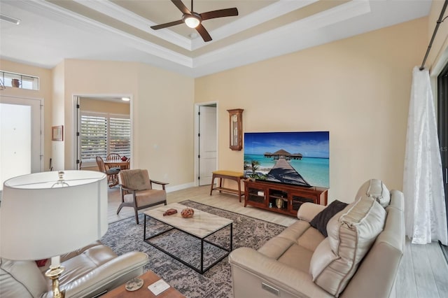 living room with light wood-type flooring, a tray ceiling, ceiling fan, and crown molding