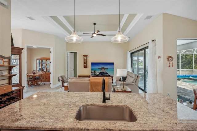 kitchen featuring light stone countertops, decorative light fixtures, light hardwood / wood-style flooring, and sink