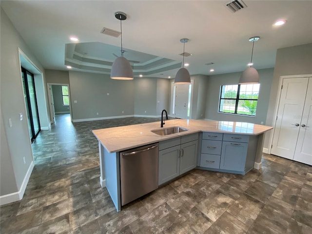 kitchen with sink, an island with sink, stainless steel dishwasher, and a tray ceiling