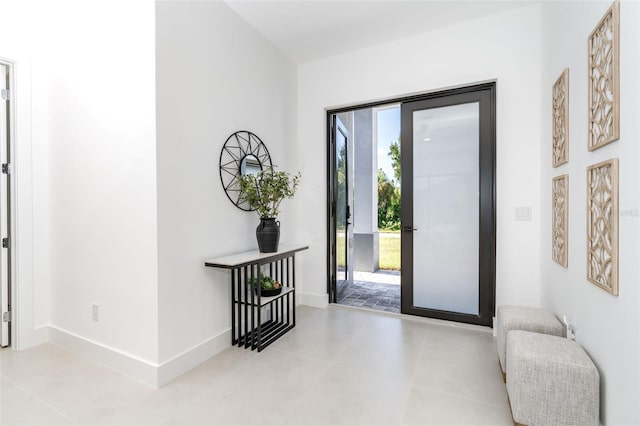 doorway to outside featuring light tile patterned floors and baseboards