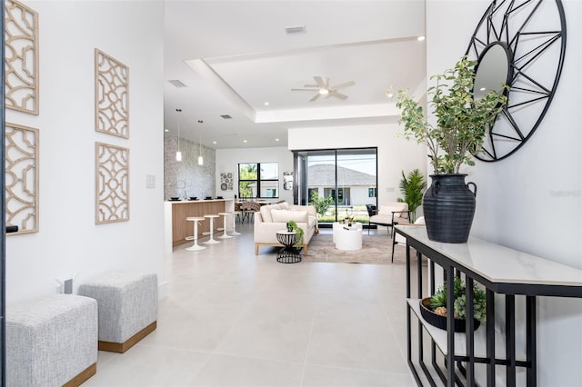 interior space with a tray ceiling, light tile patterned floors, recessed lighting, visible vents, and a ceiling fan