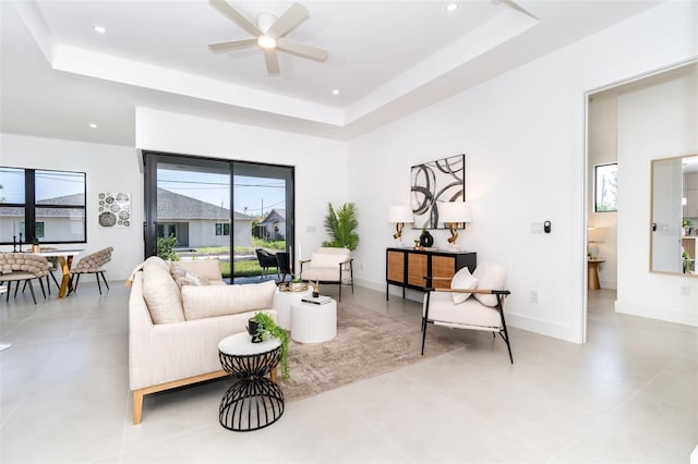 living area with light tile patterned floors, recessed lighting, a ceiling fan, baseboards, and a raised ceiling