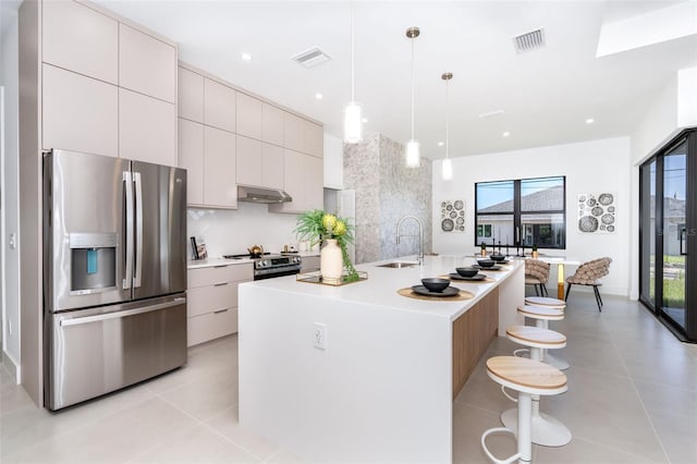 kitchen featuring a center island with sink, light countertops, hanging light fixtures, appliances with stainless steel finishes, and modern cabinets