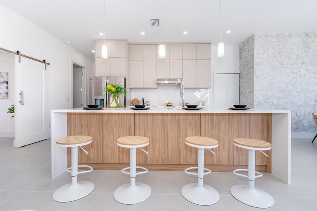 kitchen featuring a breakfast bar, white cabinets, and decorative light fixtures