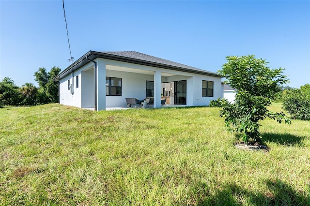 back of house featuring a yard, a patio, and stucco siding