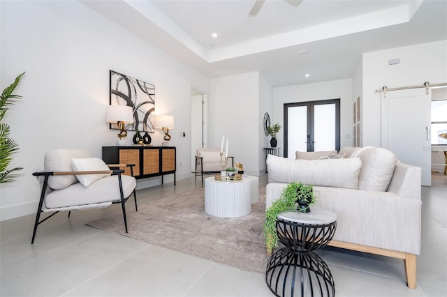 living room featuring french doors, a barn door, a tray ceiling, and recessed lighting