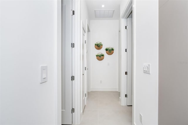 corridor featuring light tile patterned floors, visible vents, and baseboards