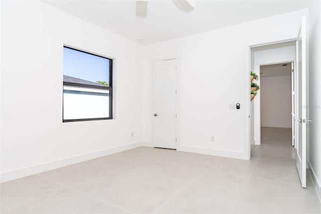 empty room featuring light tile patterned floors, ceiling fan, and baseboards