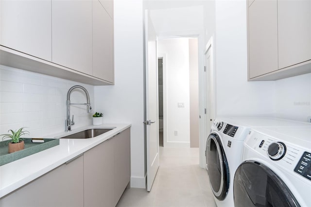 washroom with a sink, light tile patterned floors, washing machine and dryer, and cabinet space