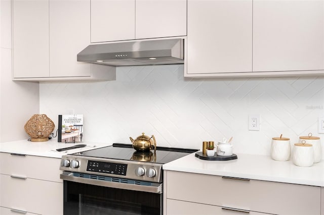 kitchen with range hood, light countertops, decorative backsplash, white cabinets, and stainless steel range with electric cooktop