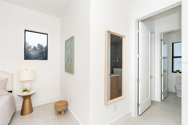 hall featuring light tile patterned flooring and baseboards