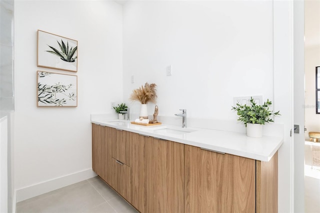 bathroom with tile patterned flooring, a sink, baseboards, and double vanity