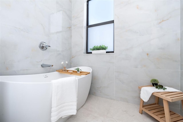 full bath featuring tile patterned flooring, a freestanding tub, and tile walls