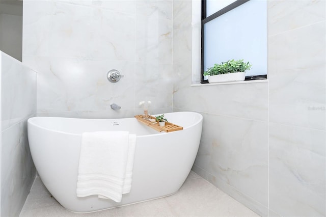 full bath featuring plenty of natural light, a soaking tub, and tile walls