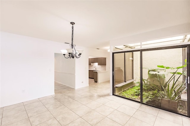 unfurnished room with a notable chandelier and light tile patterned flooring