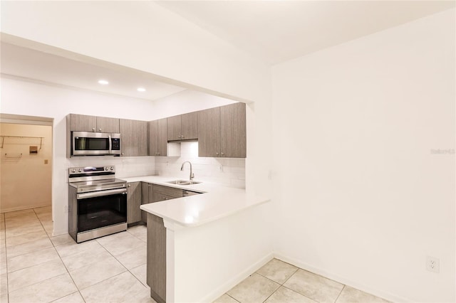 kitchen featuring backsplash, sink, light tile patterned floors, kitchen peninsula, and stainless steel appliances