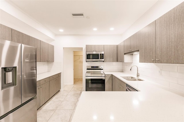 kitchen featuring decorative backsplash, light tile patterned floors, stainless steel appliances, and sink