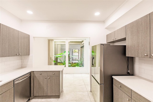 kitchen featuring stainless steel appliances, backsplash, kitchen peninsula, crown molding, and light tile patterned floors