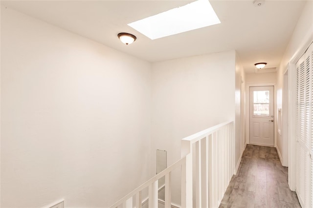 hall with light wood-type flooring and a skylight