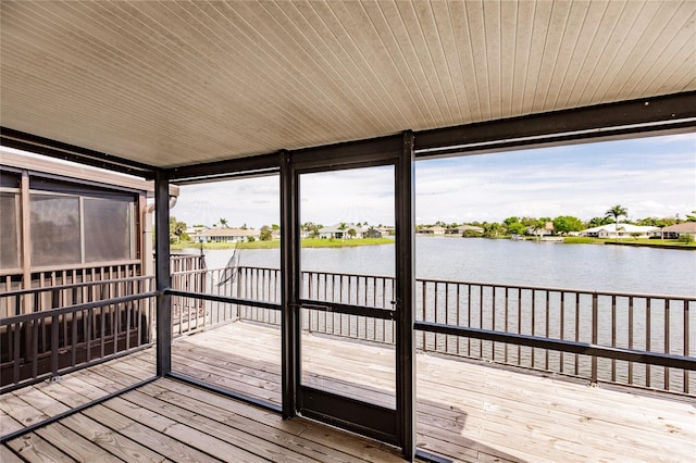 unfurnished sunroom featuring a healthy amount of sunlight, a water view, and wooden ceiling