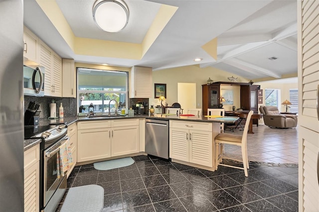 kitchen with kitchen peninsula, backsplash, dark tile flooring, sink, and appliances with stainless steel finishes