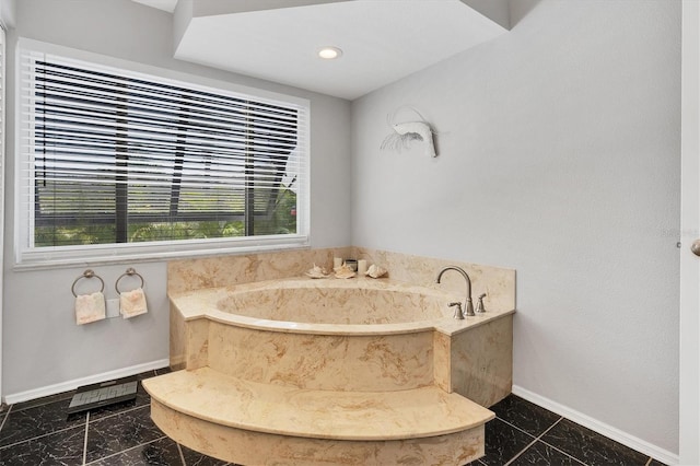 bathroom with a wealth of natural light, tile flooring, and a bath to relax in