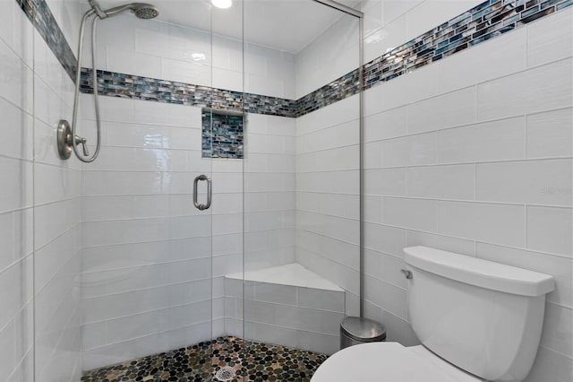 bathroom featuring tile walls, walk in shower, and toilet