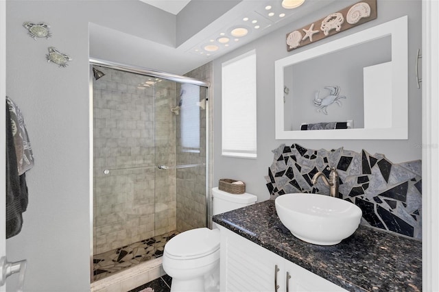 bathroom with oversized vanity, toilet, and a shower with door