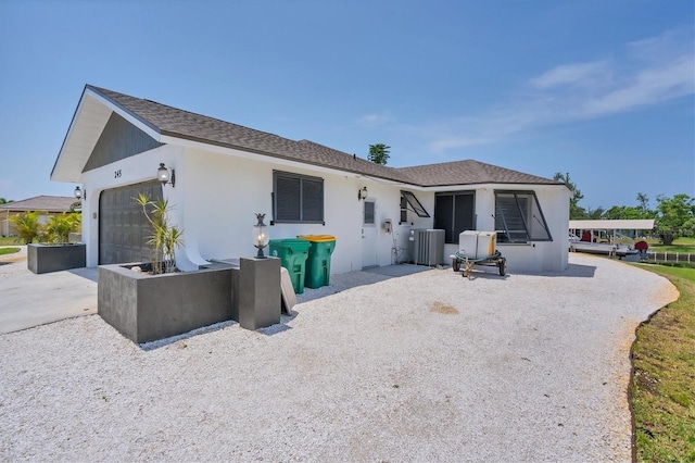 back of property with a garage and central AC unit