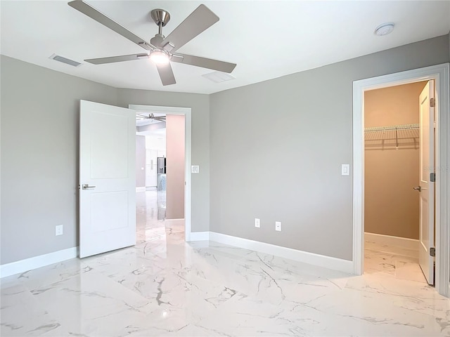 unfurnished bedroom with a walk in closet, a closet, and ceiling fan