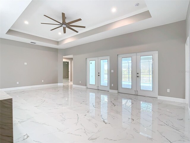 unfurnished room with a raised ceiling, ceiling fan, and french doors