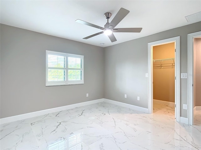 unfurnished bedroom with a walk in closet, a closet, and ceiling fan