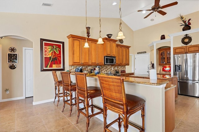 kitchen featuring high vaulted ceiling, ceiling fan, tasteful backsplash, decorative light fixtures, and stainless steel appliances