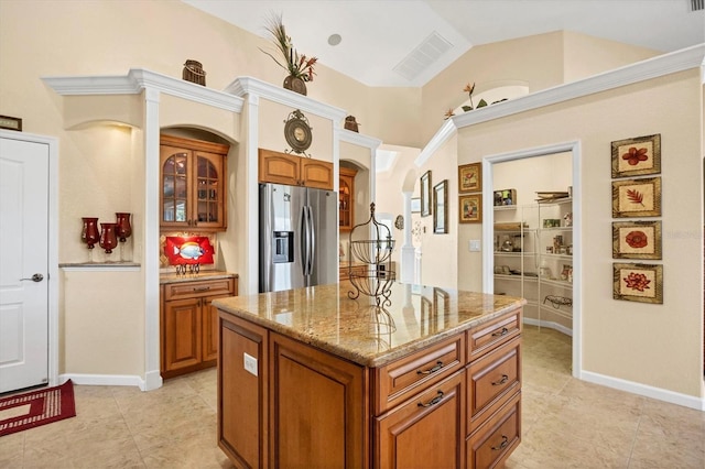 kitchen with stainless steel refrigerator with ice dispenser, light stone counters, vaulted ceiling, light tile patterned floors, and a kitchen island