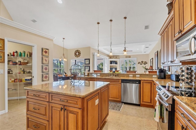 kitchen with pendant lighting, a center island, ceiling fan with notable chandelier, sink, and appliances with stainless steel finishes