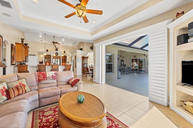 tiled living room with a tray ceiling, ceiling fan, and ornamental molding